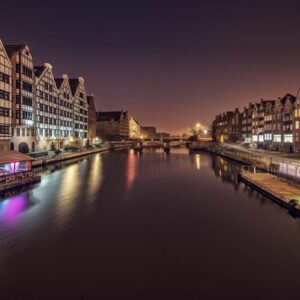 Water channel between multistage building exteriors and shiny lights at dusk in Amsterdam Netherlands