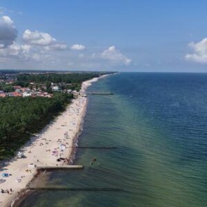 A breathtaking aerial shot of a sandy beach, vibrant ocean, and coastal town under a clear blue sky.