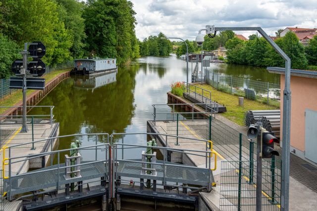 Tranquil canal lock with lush trees and calm waters, perfect for a serene boat trip.
