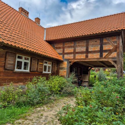 Charming rustic wooden house featuring a red tile roof and lush garden outdoor view.
