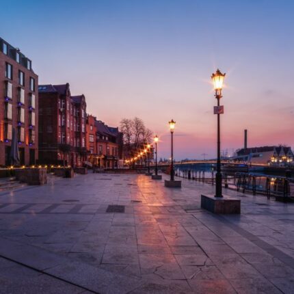 Scenic twilight view of Gdańsk waterfront featuring architecture and ferris wheel.
